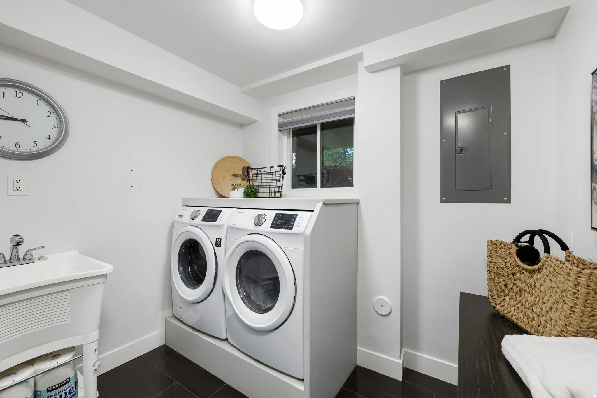 Laundry room with dark floor tiling, white walls, and a utility sink with chrome faucet