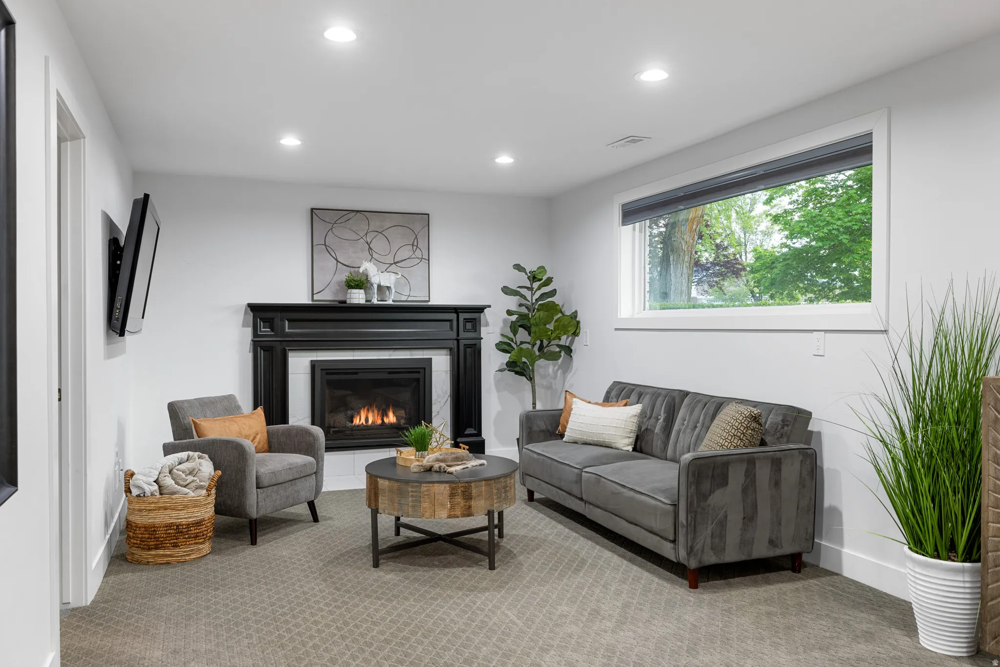 Living area featuring a black fireplace with a white tile surround, recessed lighting, and a large window