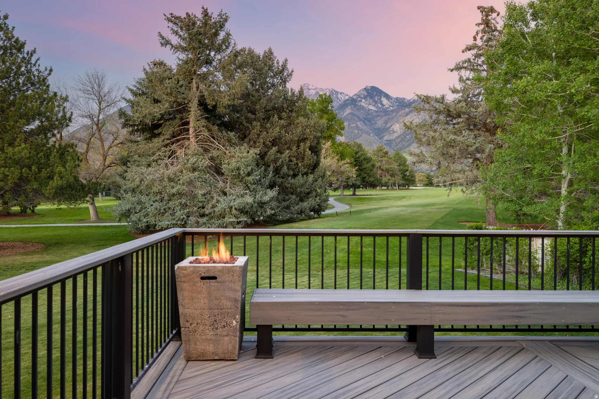 Spacious outdoor deck featuring wood-finish flooring, a built-in bench, and a concrete-finish fire pit