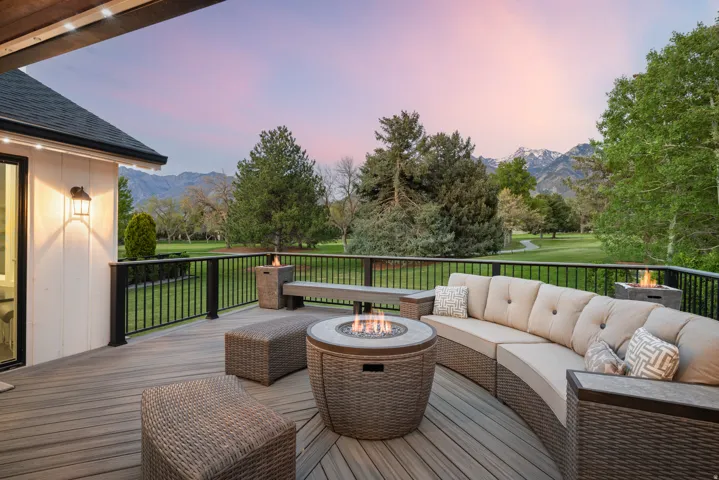 Spacious outdoor deck featuring composite decking, black metal railings, and a built-in fire pit