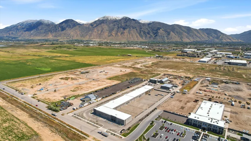 Expansive land parcel featuring existing commercial structures, paved roadways, and a backdrop of snow-capped mountains