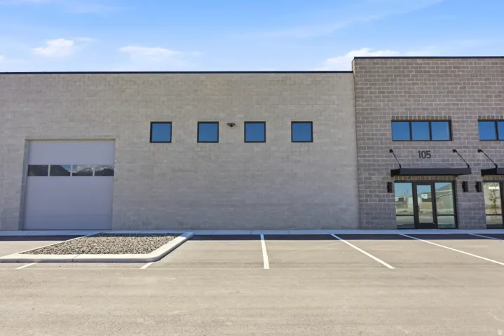 Commercial building featuring a roll-up garage door, multiple windows, and a prominent entrance with a dark awning