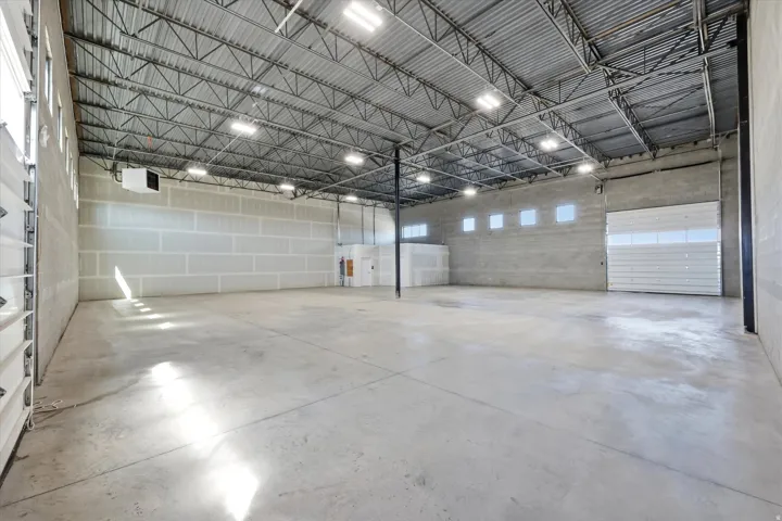 Expansive industrial space featuring a concrete floor, exposed metal truss ceiling, and ample overhead lighting