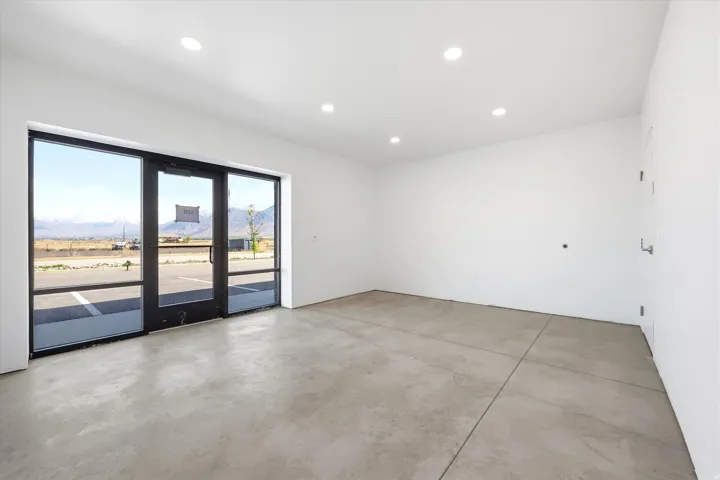 Expansive commercial space featuring a full-glass storefront with a black frame and concrete flooring