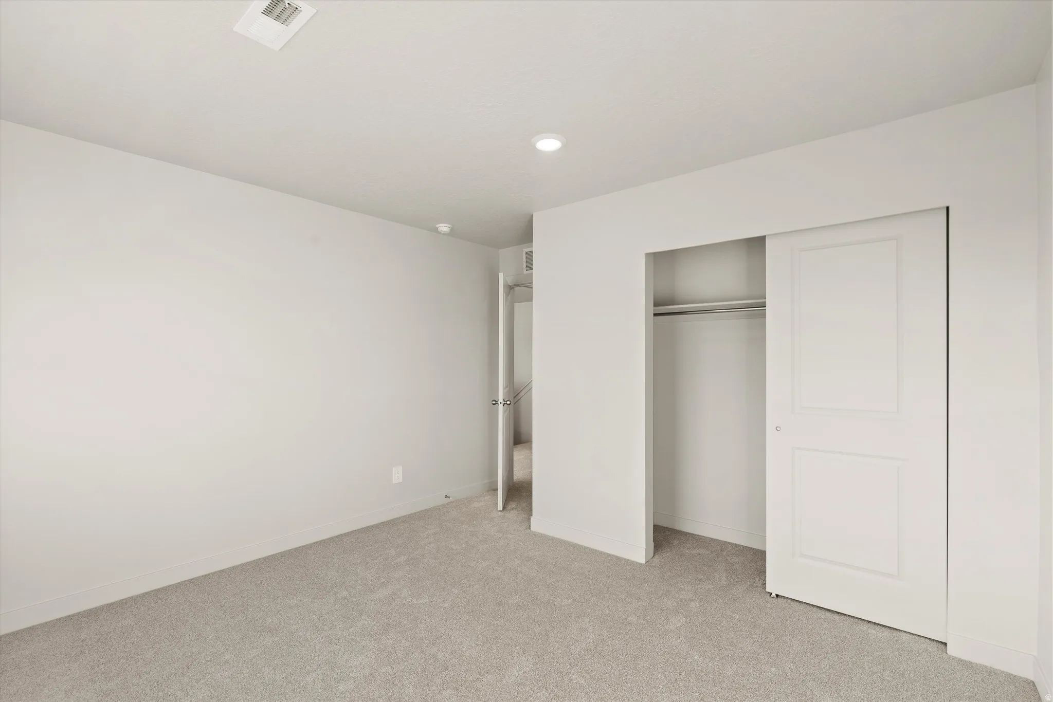 Neutral-toned room featuring light gray carpet flooring and recessed ceiling lighting