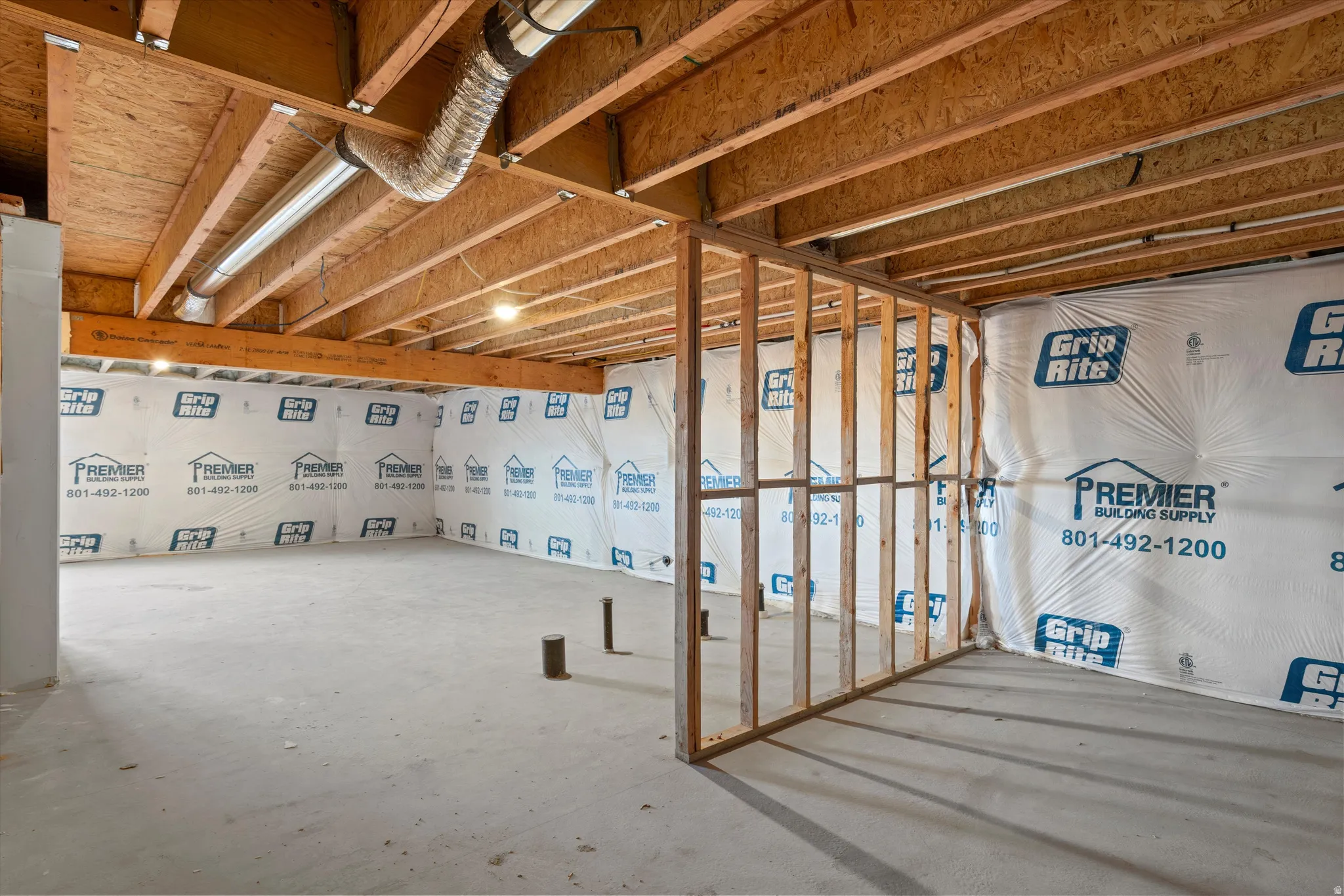 Unfinished basement space featuring exposed wood joists, concrete flooring, and partial wood framing for future customization