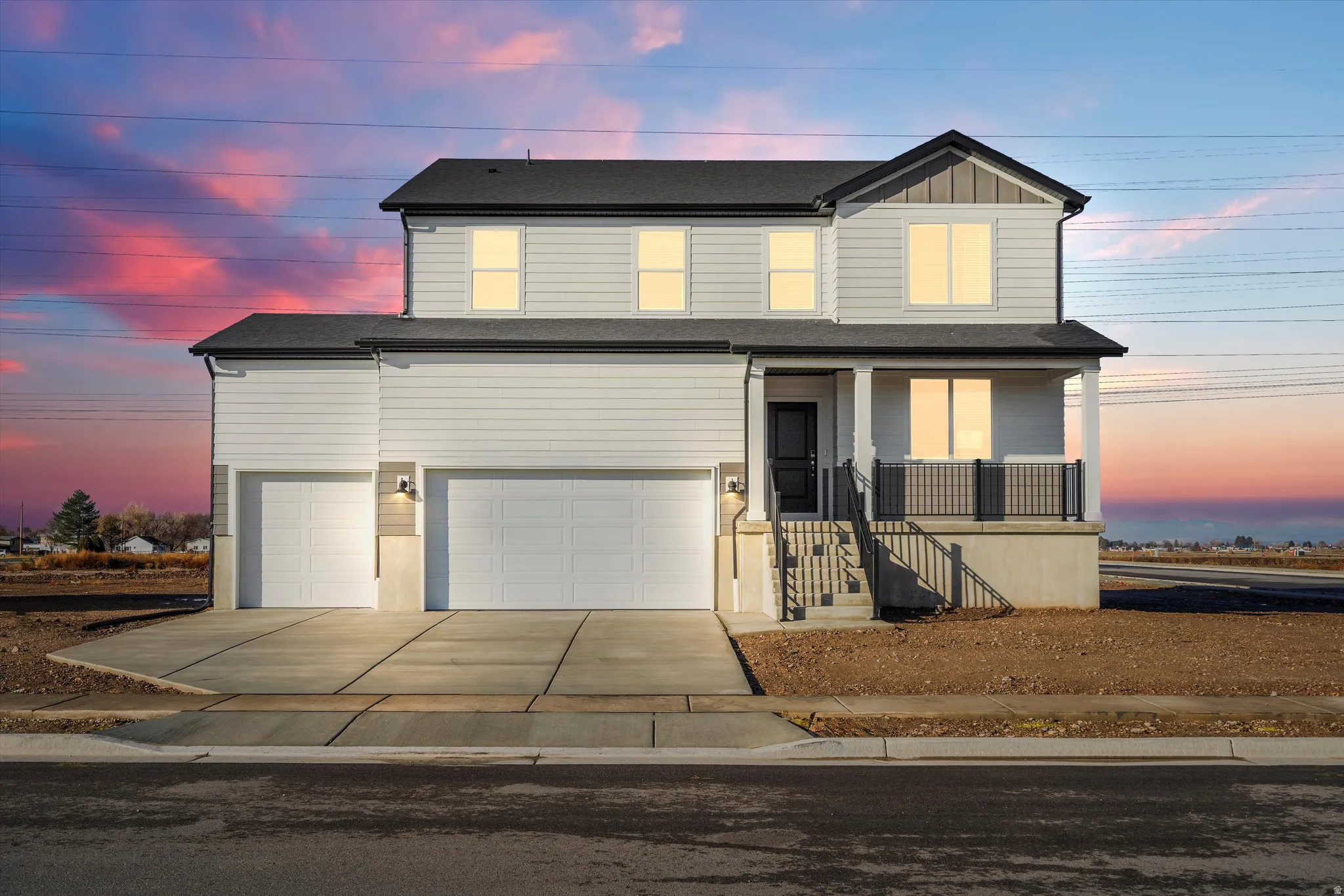 Two-story contemporary residence featuring white horizontal siding, a covered front porch with dark railings, a two-car garage, an additional single-car garage, and dark shingle roofing