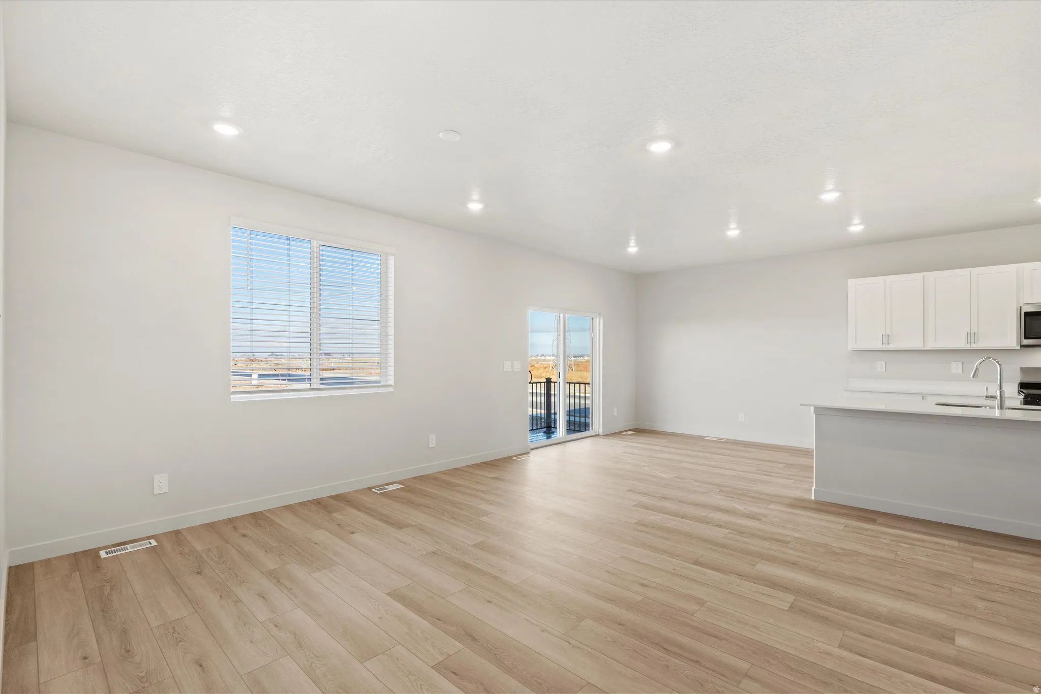 Open-concept living area featuring wood-finish flooring, recessed lighting, and light-toned wall finishes