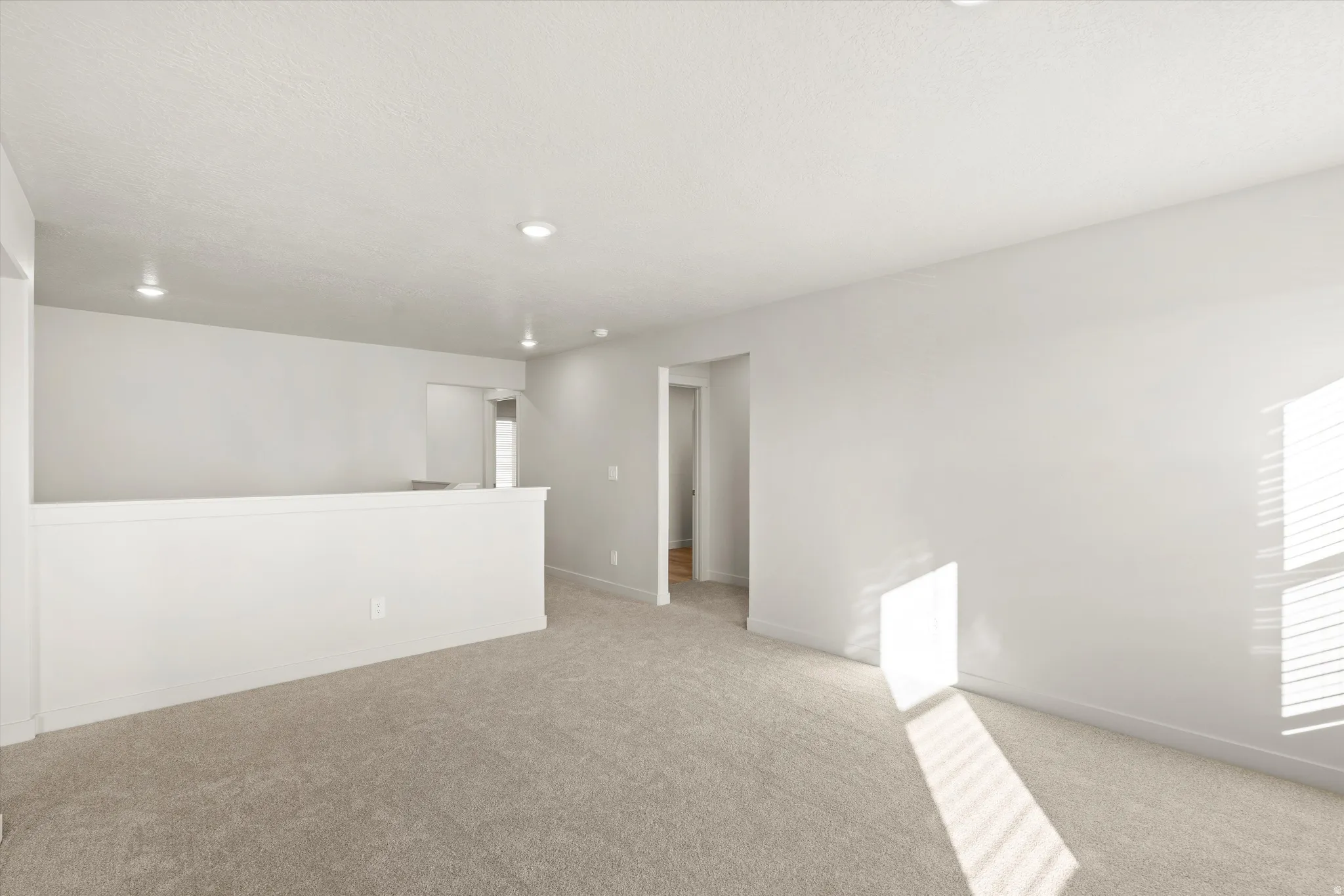 Spacious interior featuring a neutral color palette, plush carpeting, recessed lighting, and crisp white trim