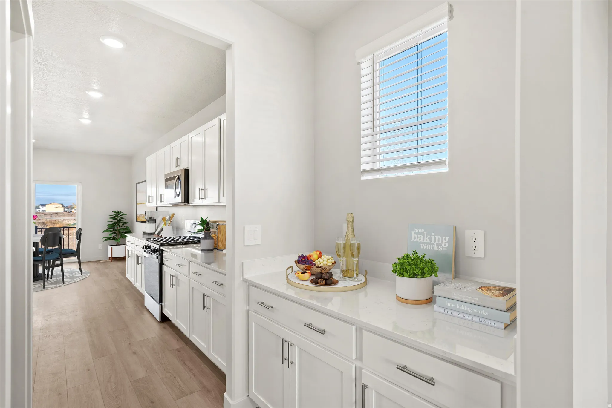 Contemporary kitchen featuring white cabinetry, stainless steel appliances, wood-finish flooring, recessed lighting, and a built-in countertop with additional storage