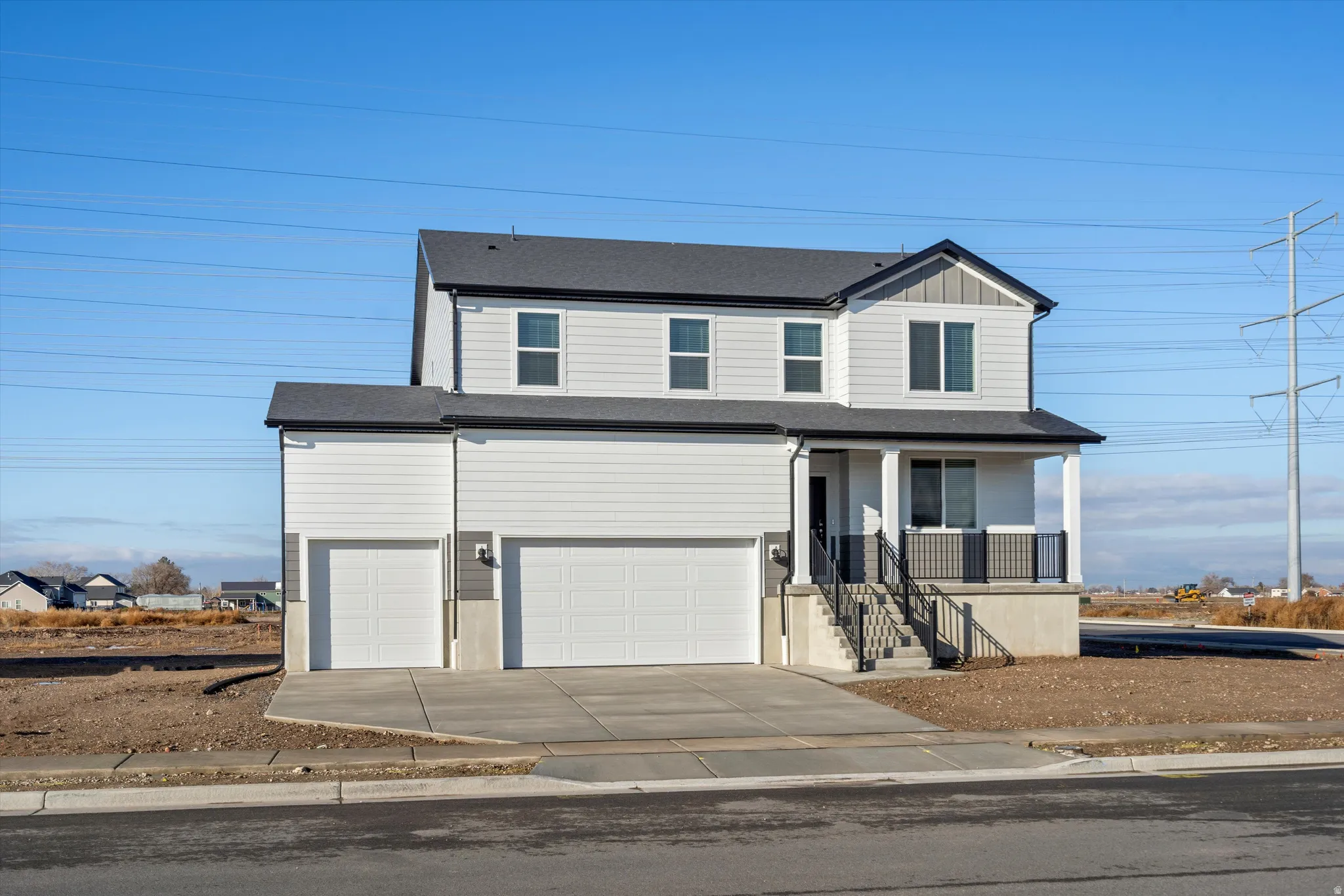 Two-story residence featuring a covered front porch, white siding, dark gray accents, a two-car garage, and an additional single-car garage