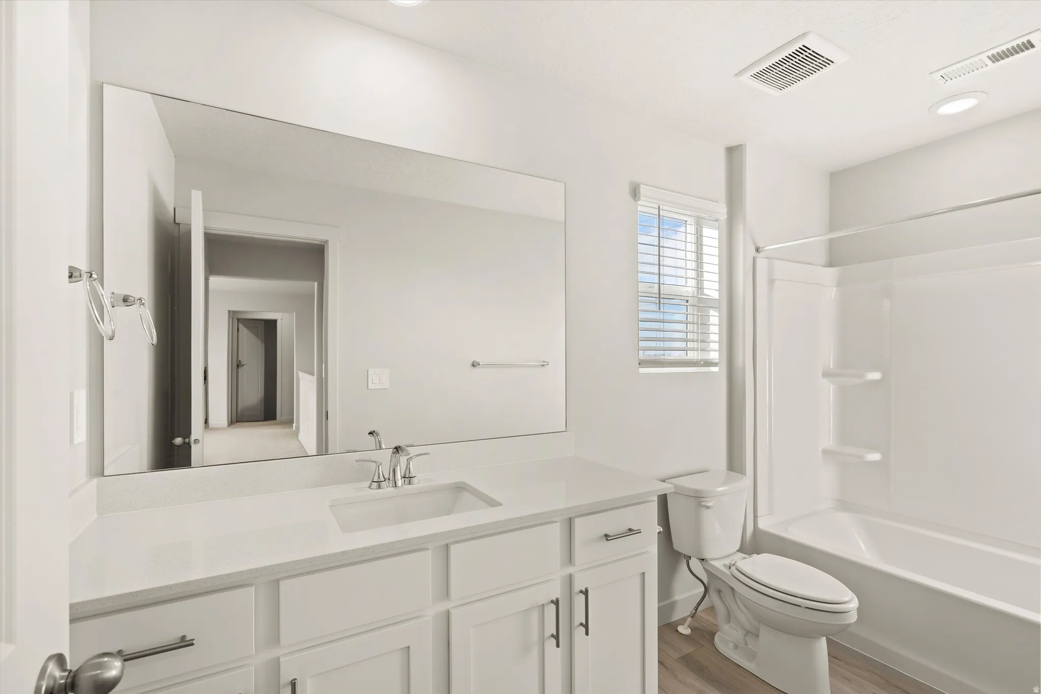 Bathroom featuring a white vanity with an integrated sink, polished chrome faucet, and a large wall-mounted mirror
