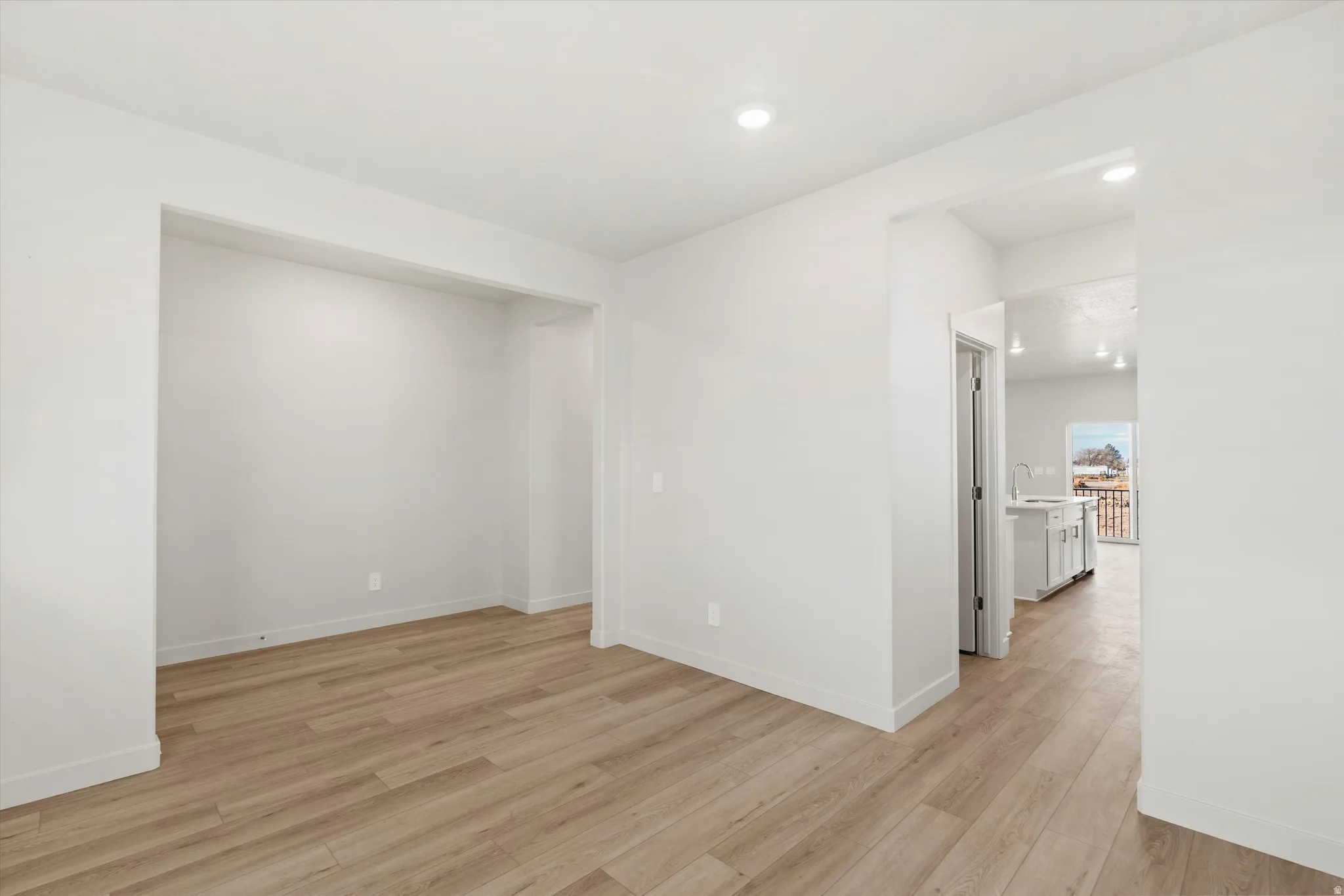 Spacious room featuring light wood-finish flooring, recessed lighting, and a neutral color palette