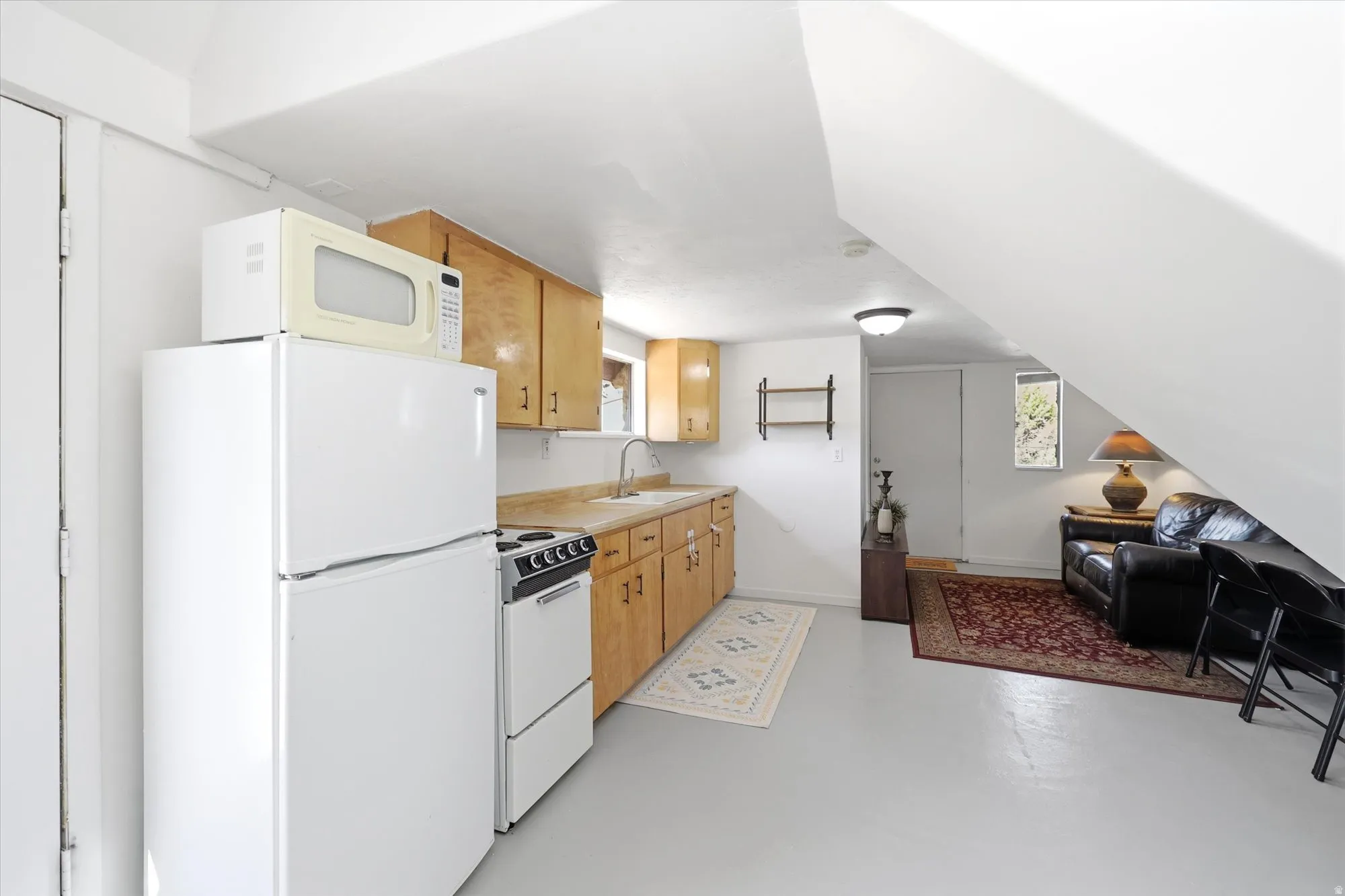 Kitchen with white appliances, open floor plan, concrete floors, and light countertops