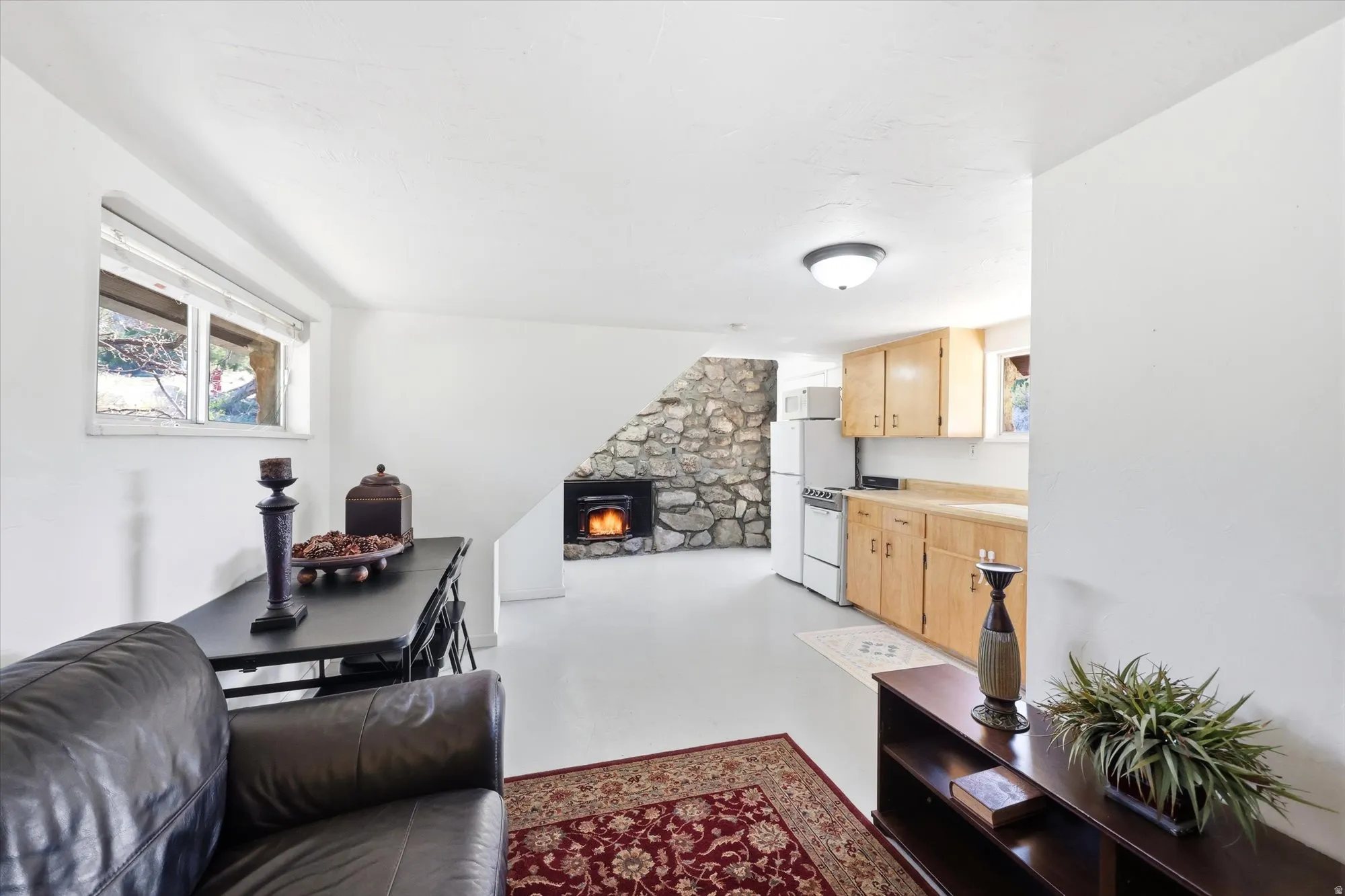 Living area featuring concrete floors, healthy amount of natural light, and a stone fireplace