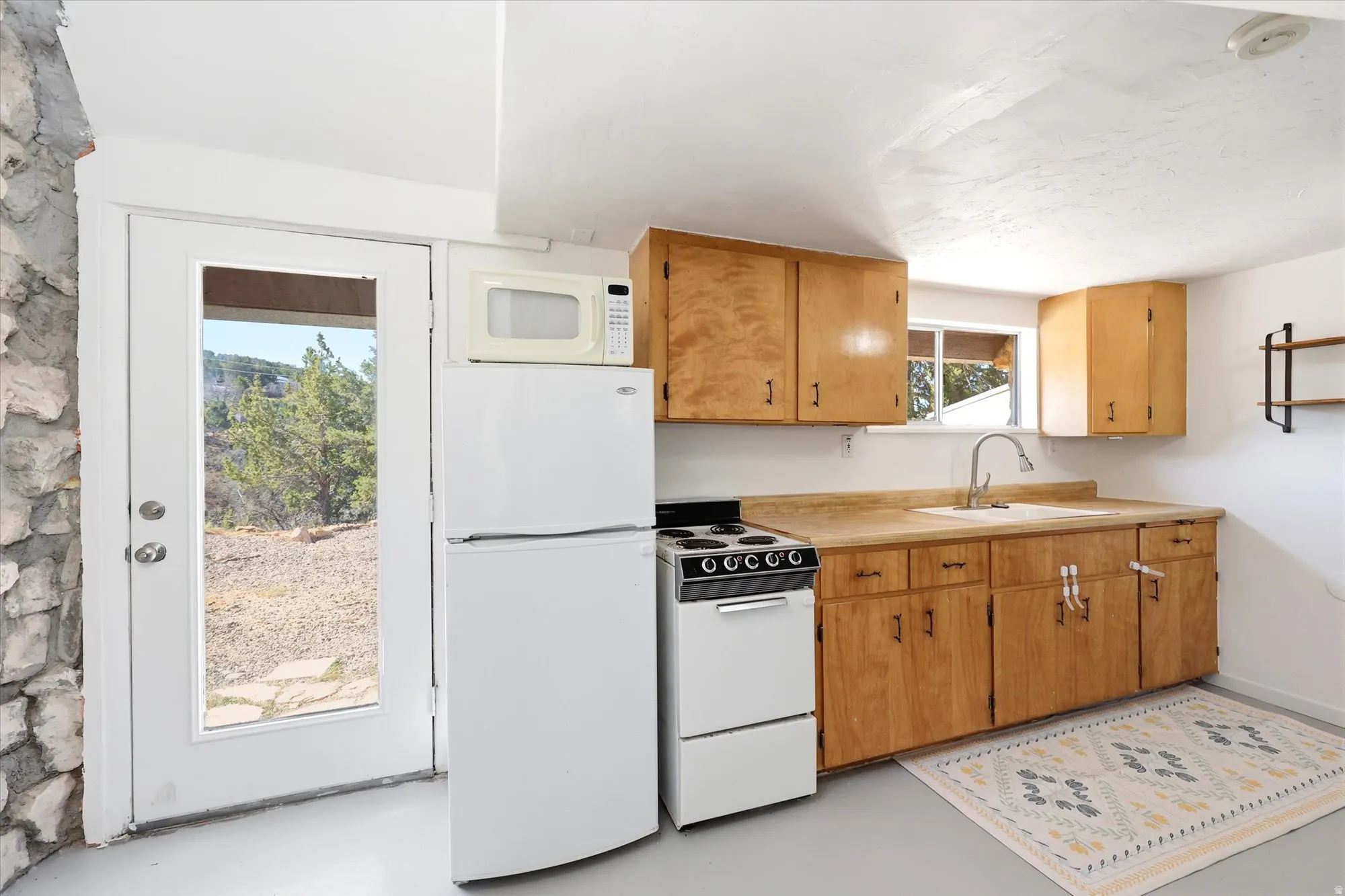 Kitchen featuring white appliances, light countertops, finished concrete floors, and wood finish cabinets