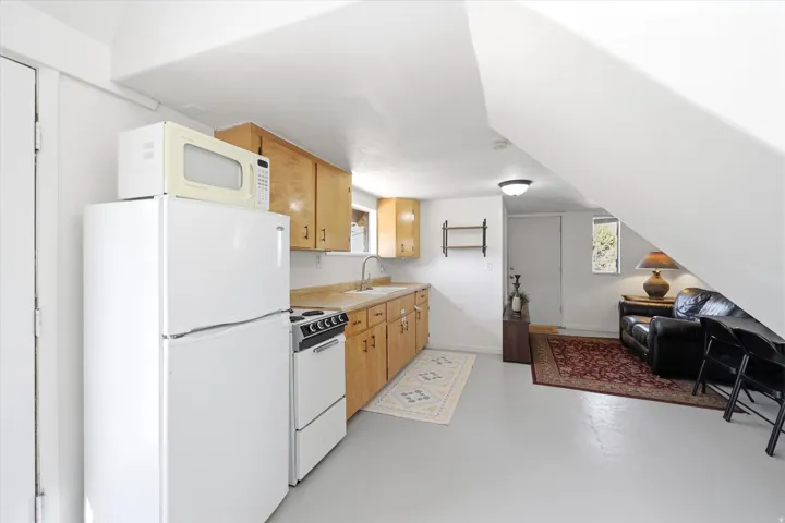 Kitchen with white appliances, open floor plan, concrete floors, and light countertops