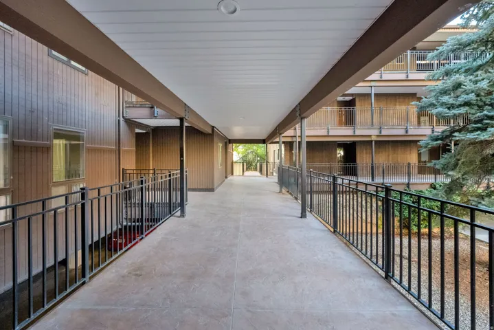 Covered exterior walkway featuring a concrete surface and black metal railings