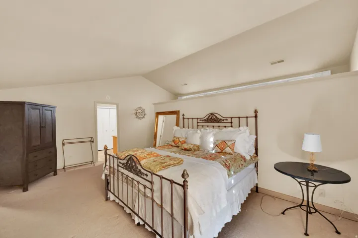 Carpeted room with a vaulted ceiling and a high shelf feature