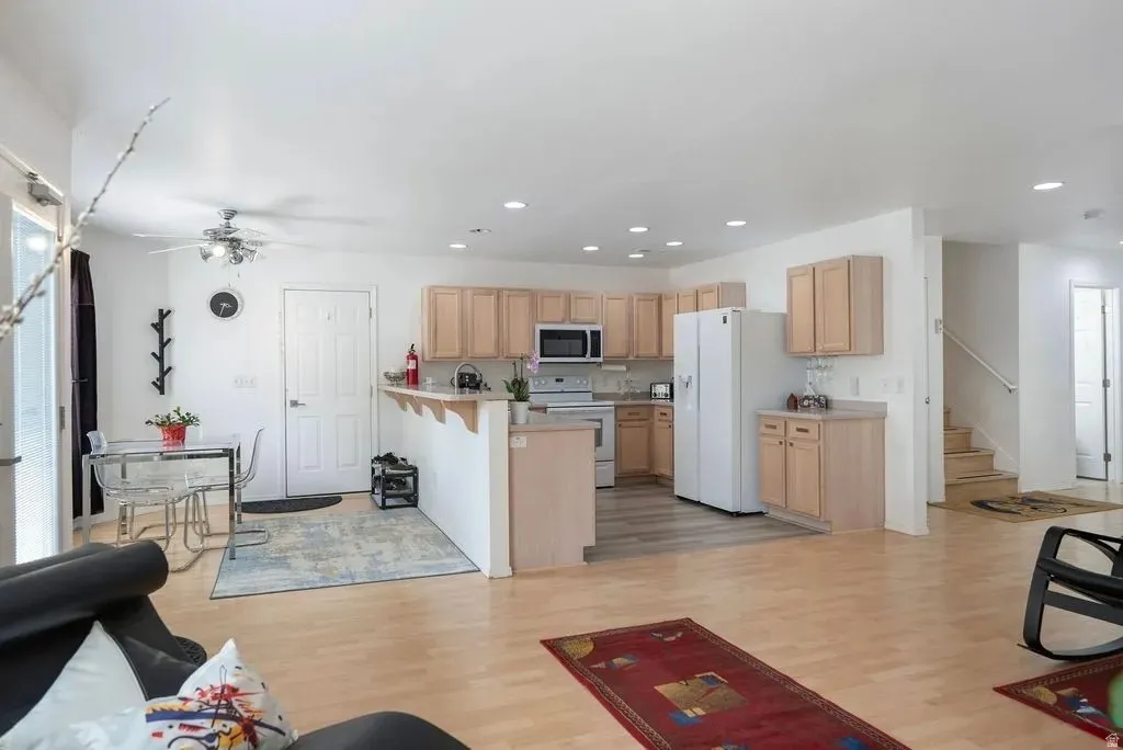 Open concept living area featuring light wood-finish flooring, recessed lighting, and a kitchen with light wood cabinetry