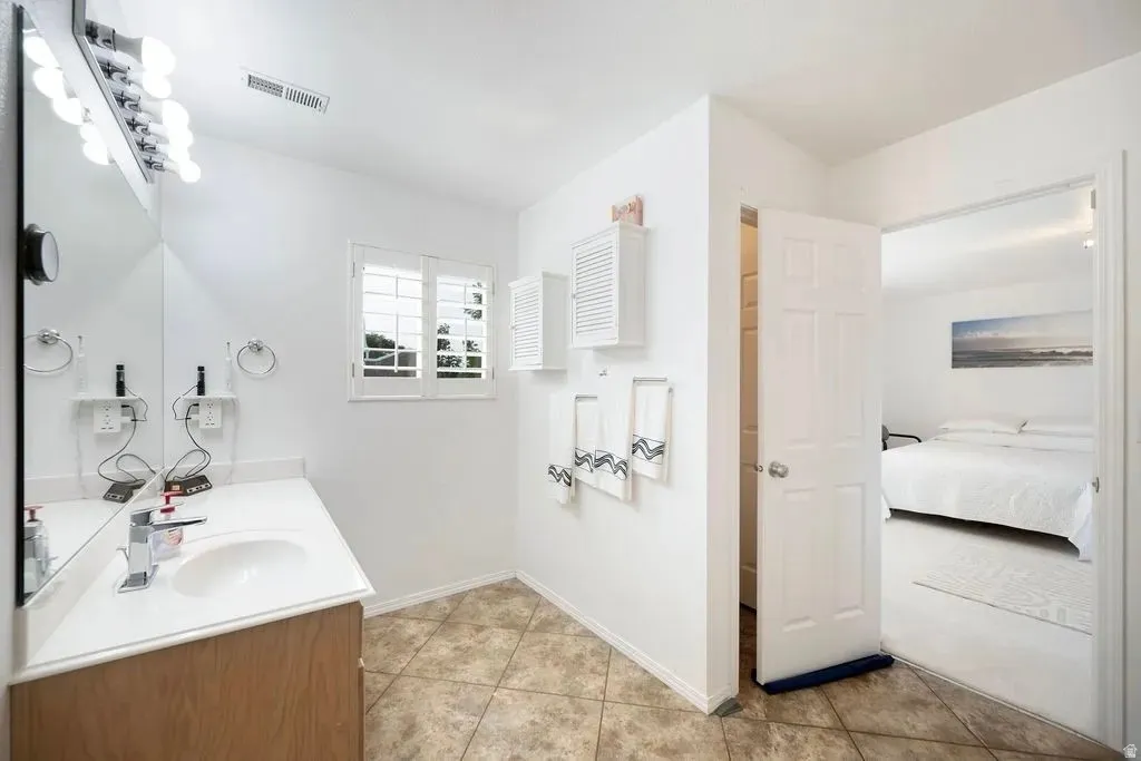 Bathroom featuring a single vanity with a solid surface countertop, integrated sink, and wood-finish cabinetry