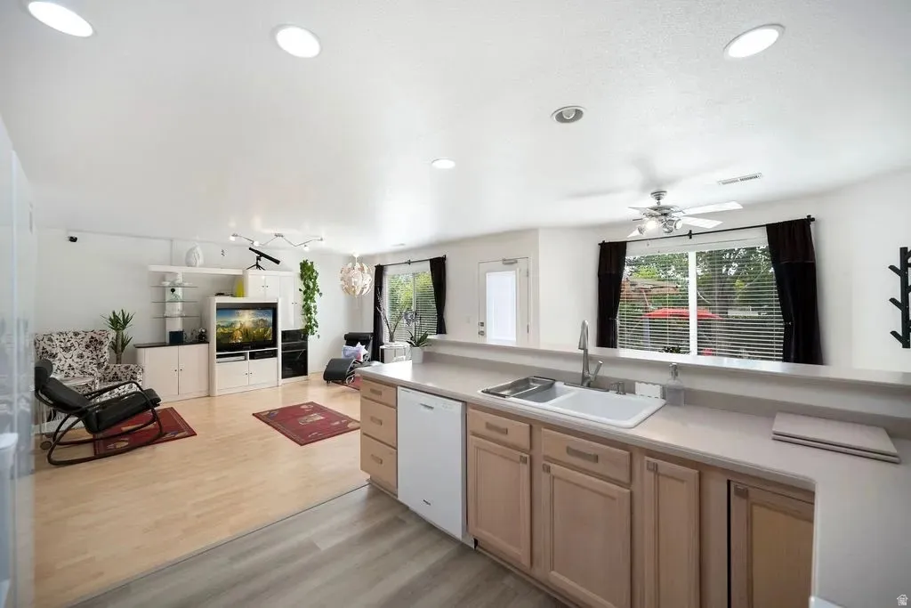 Kitchen pass-through with wood-finish cabinetry, a double basin sink, and laminate countertops