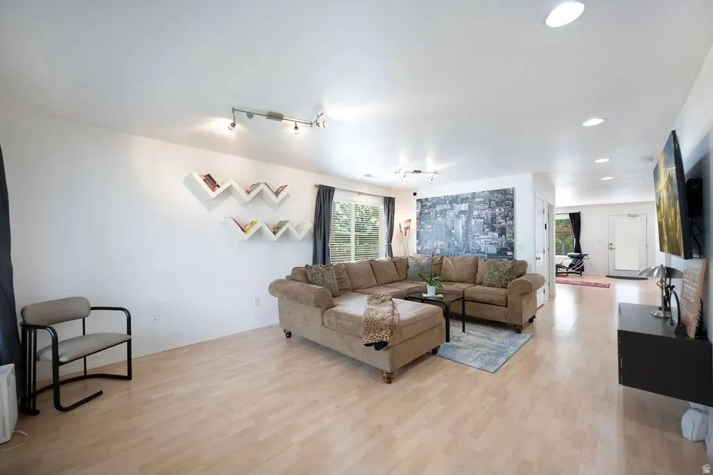 Open-concept living space with light wood-finish flooring, recessed lighting, and track lighting fixtures