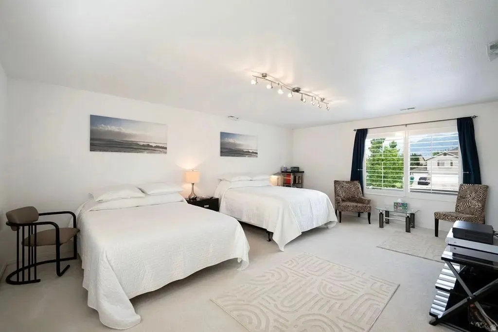Spacious interior room featuring white walls and light-toned carpeting