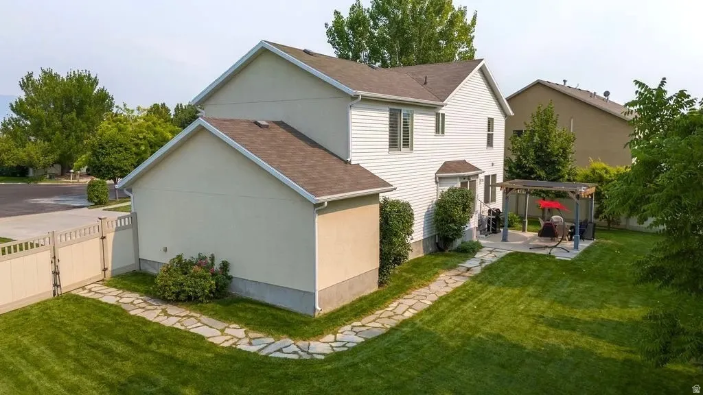 Expansive backyard featuring a lush lawn, a flagstone pathway, a privacy fence, and a patio with a built-in pergola