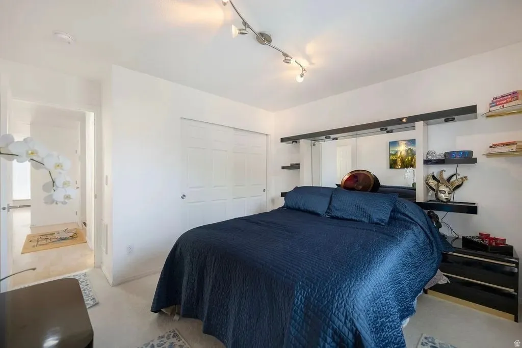Light-filled room featuring track lighting, white walls, light-toned flooring, and a mirrored wall with integrated shelving