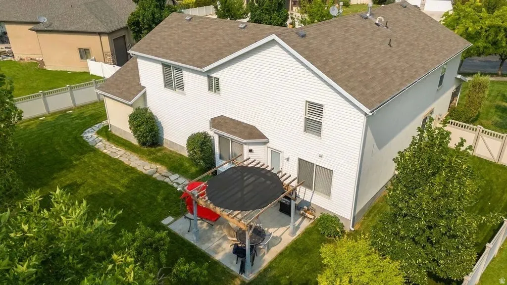 Expansive backyard featuring a stone paver patio, a wooden pergola, and established landscaping