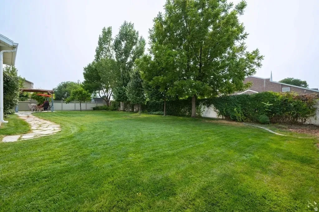 Expansive green lawn with mature trees and a stone pathway leading to a patio area