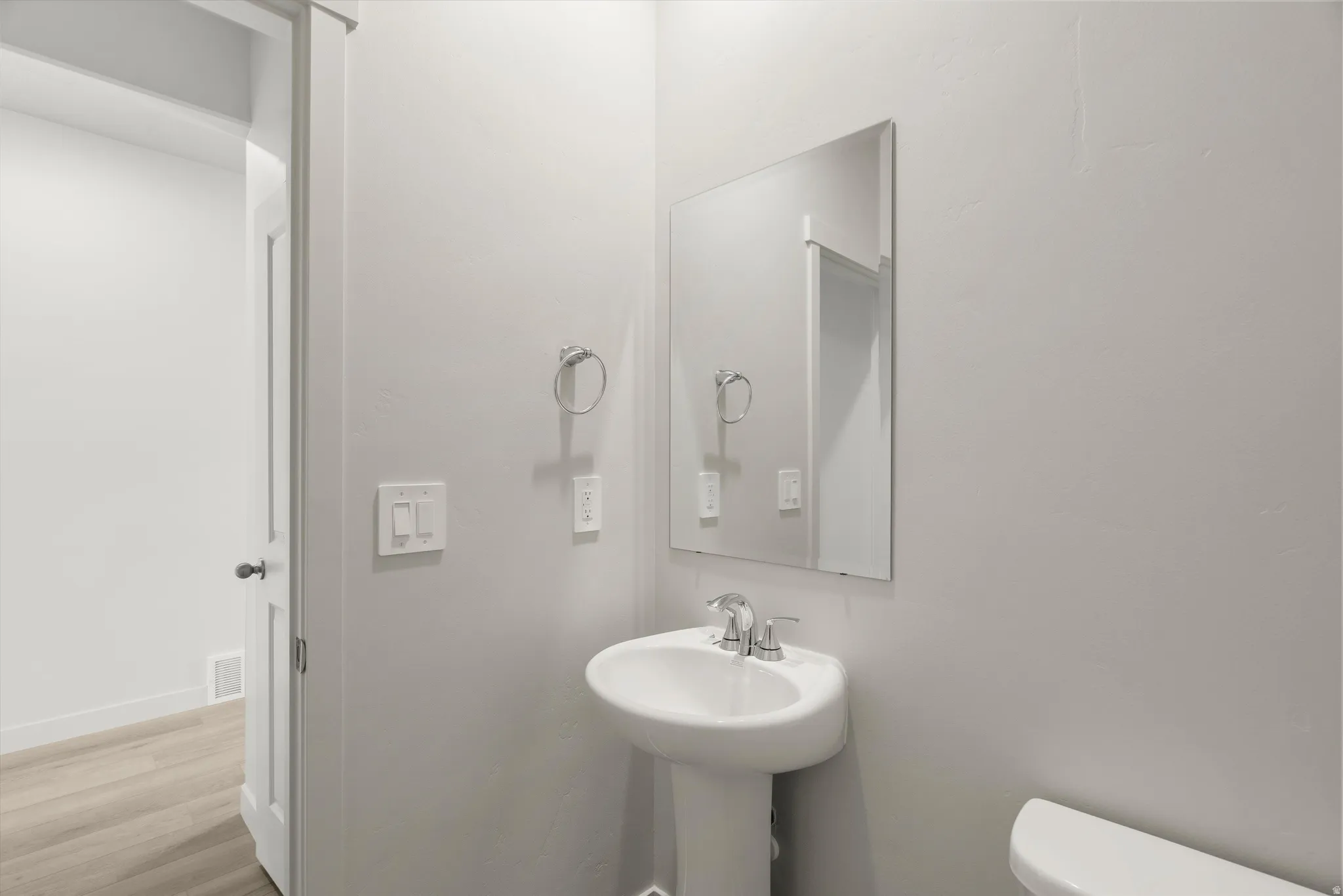 Pedestal sink with chrome faucet, framed mirror, and white toilet