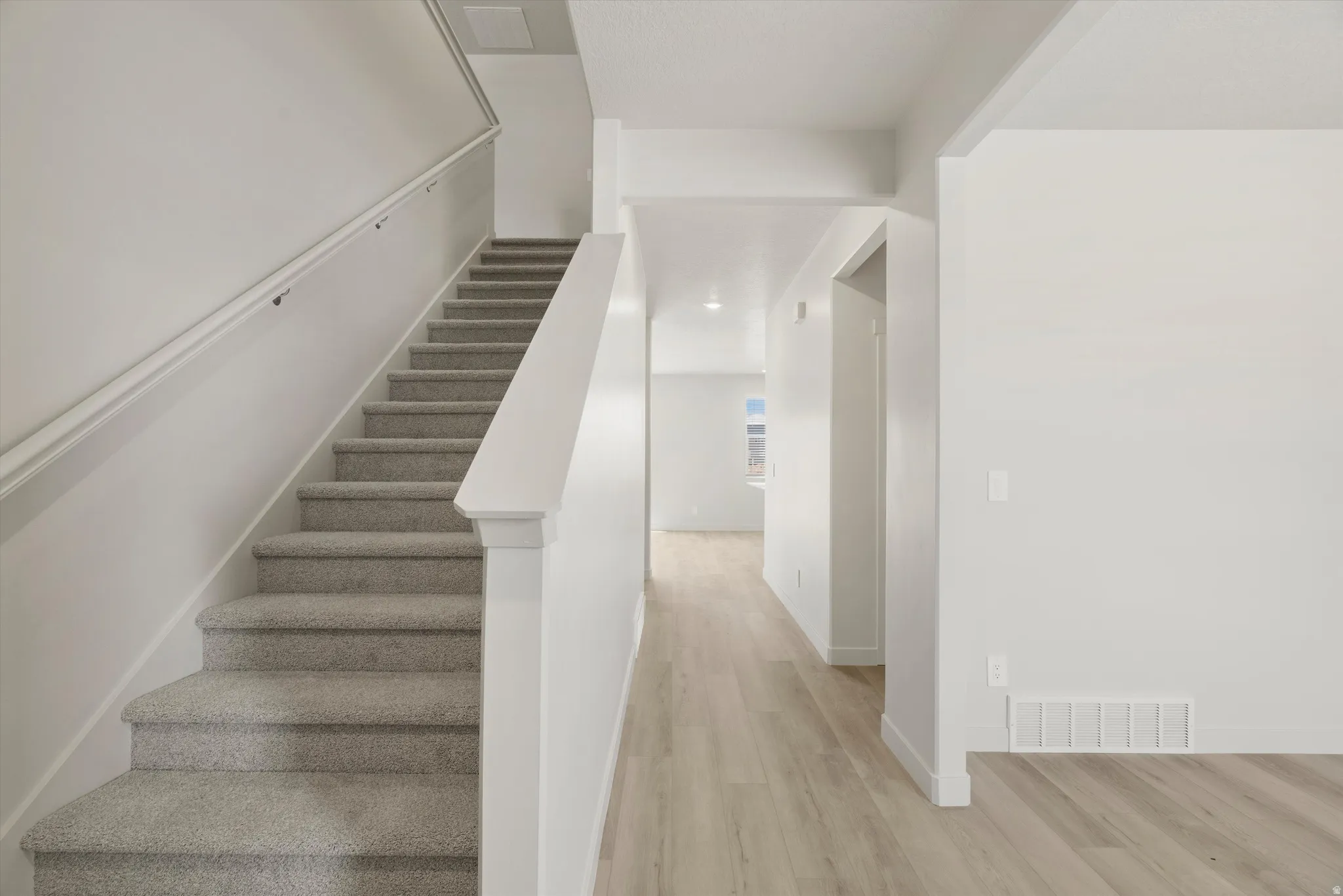 Carpeted staircase featuring a painted wood handrail and square newel post