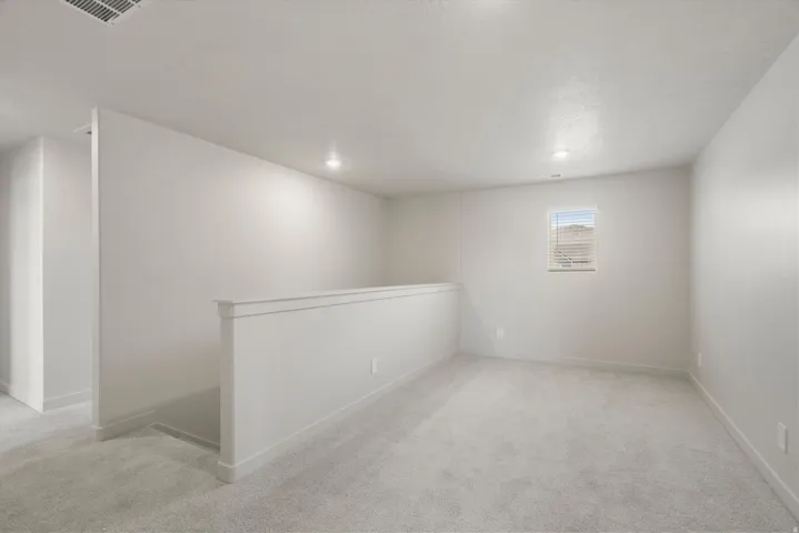 Carpeted upper-level bonus room featuring recessed lighting, a window with blinds, and a half-wall partition