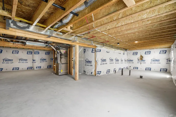 Unfinished basement featuring exposed wood joists, concrete flooring, and prepped walls with insulation and vapor barrier