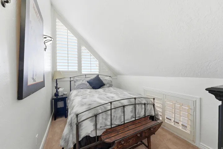 Carpeted bedroom with vaulted ceiling and baseboards