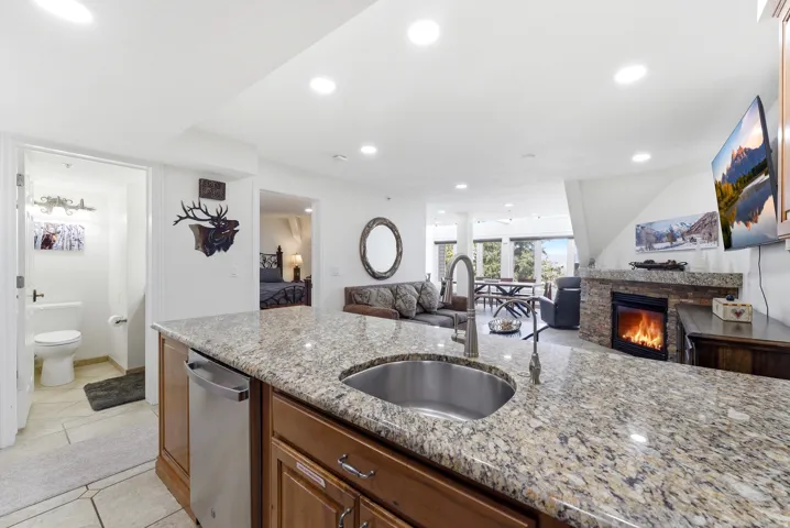 Kitchen featuring open floor plan, recessed lighting, light stone countertops, a glass covered fireplace, and light tile patterned floors