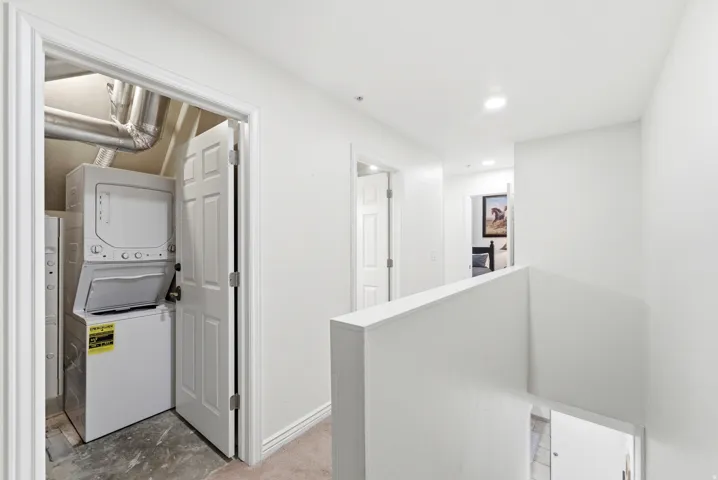 Laundry room featuring stacked washer and clothes dryer and recessed lighting
