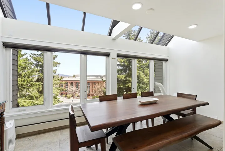 Dining room with a skylight, a baseboard radiator, recessed lighting, light tile patterned floors, and a high ceiling