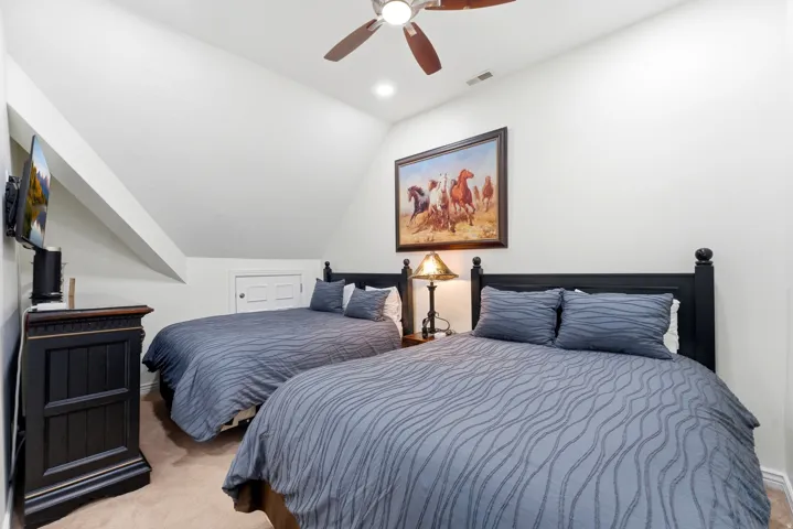Bedroom featuring vaulted ceiling, light colored carpet, and a ceiling fan