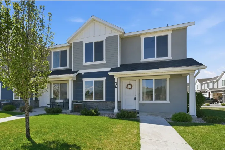 Multi-level residence featuring a gray and blue facade with white trim, stone veneer accents, and a covered entry
