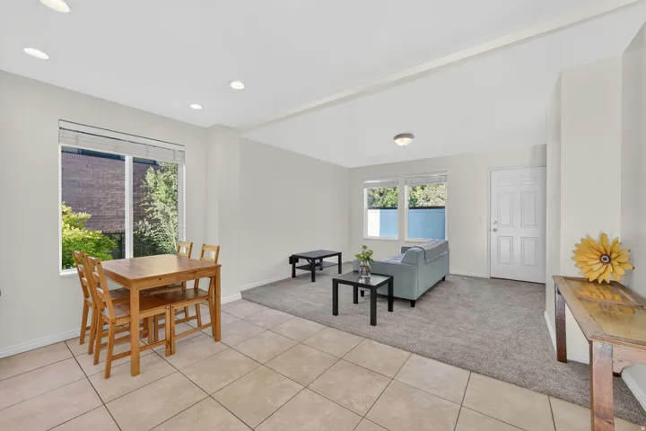 Open-concept living area featuring tile flooring, recessed lighting, neutral paint, a paneled entry door, and a carpeted lounge area