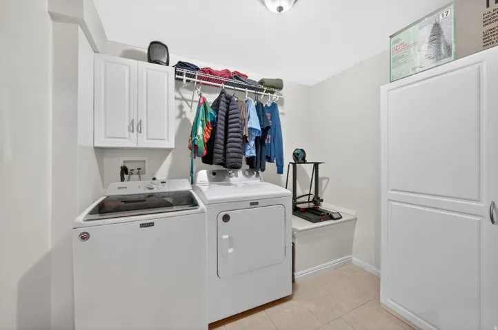 Laundry room featuring white cabinetry, a wire shelving system, a built-in bench, and tile flooring