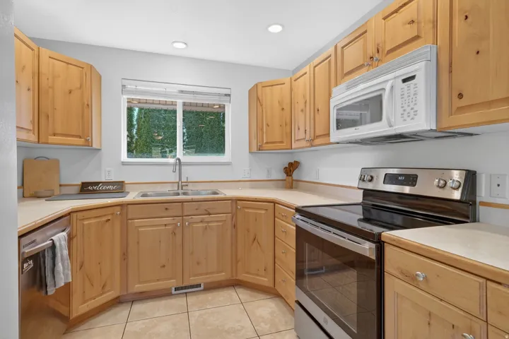 Kitchen featuring wood cabinetry, light-toned countertops, and a window above the double-basin sink