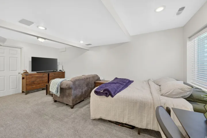 Basement carpeted room featuring recessed lighting and a window with blinds