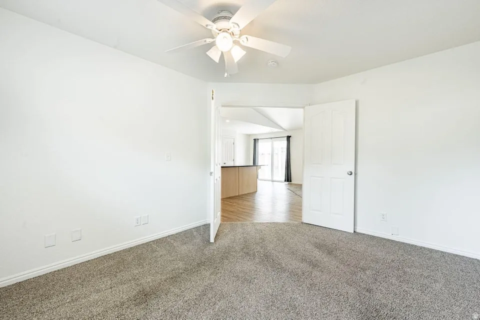 Carpeted interior room with a ceiling fan light fixture