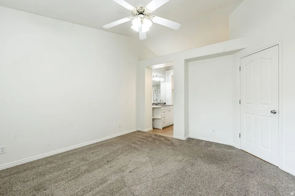 Spacious interior room with neutral gray carpet and white baseboards
