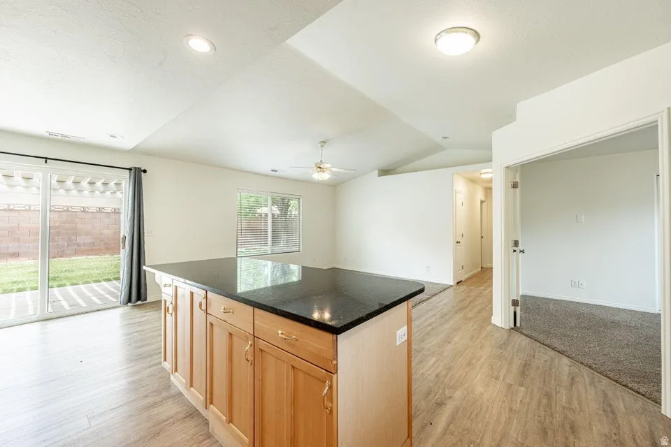 Kitchen island with wood cabinetry and dark countertop