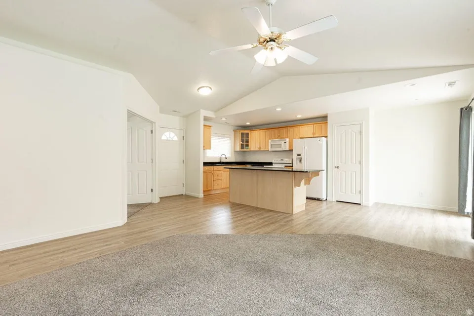 Vaulted ceilings in an open-concept living area with a ceiling fan